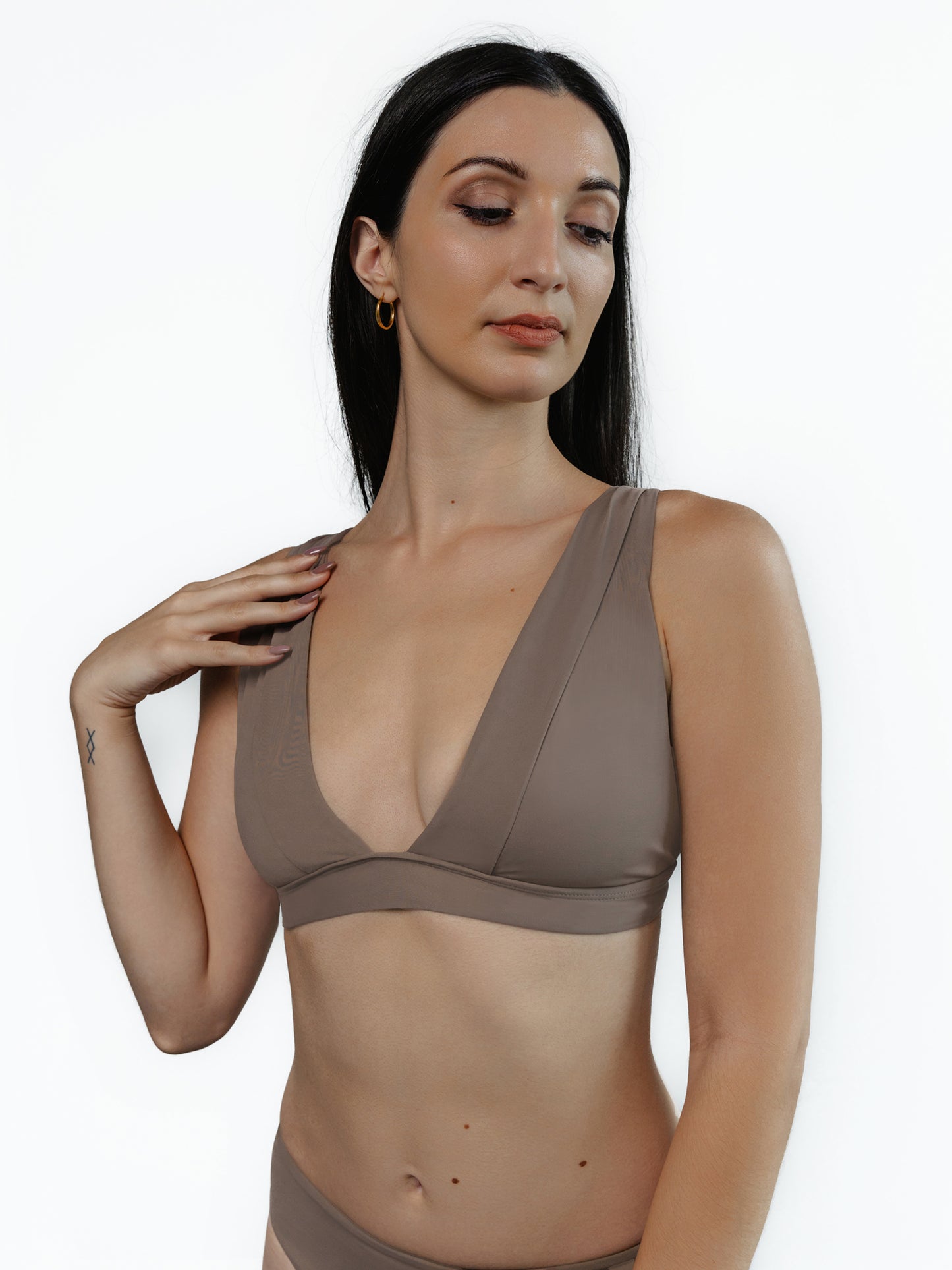 Closeup frontside of female model wearing the Eva bikini halter top in Truffle color. The model is standing in front of a white background.